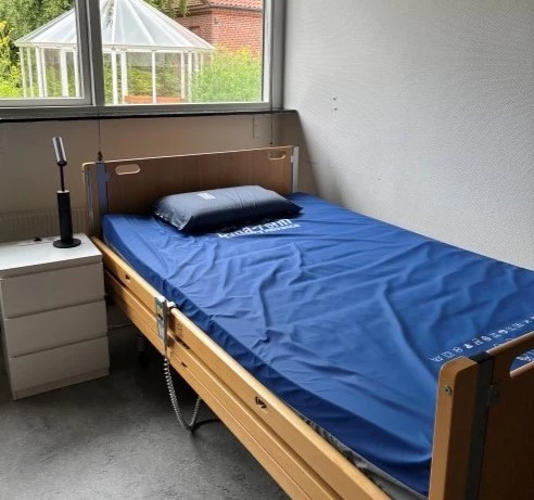 Værelse med seng op ad væg og udsigt til have
